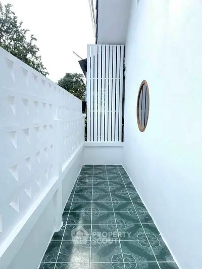 Charming outdoor balcony with stylish green tiles and modern white walls.