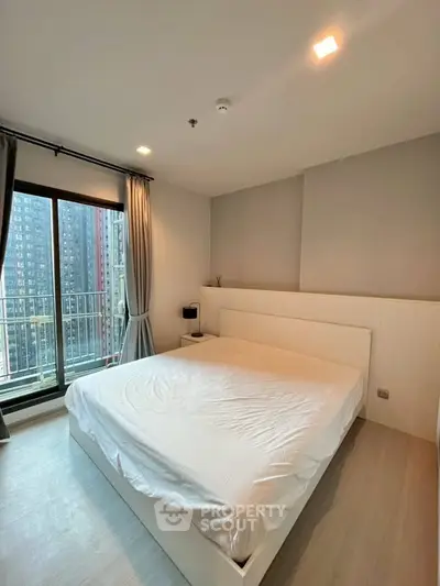 Modern bedroom with large window and city view, featuring sleek design and ample natural light.