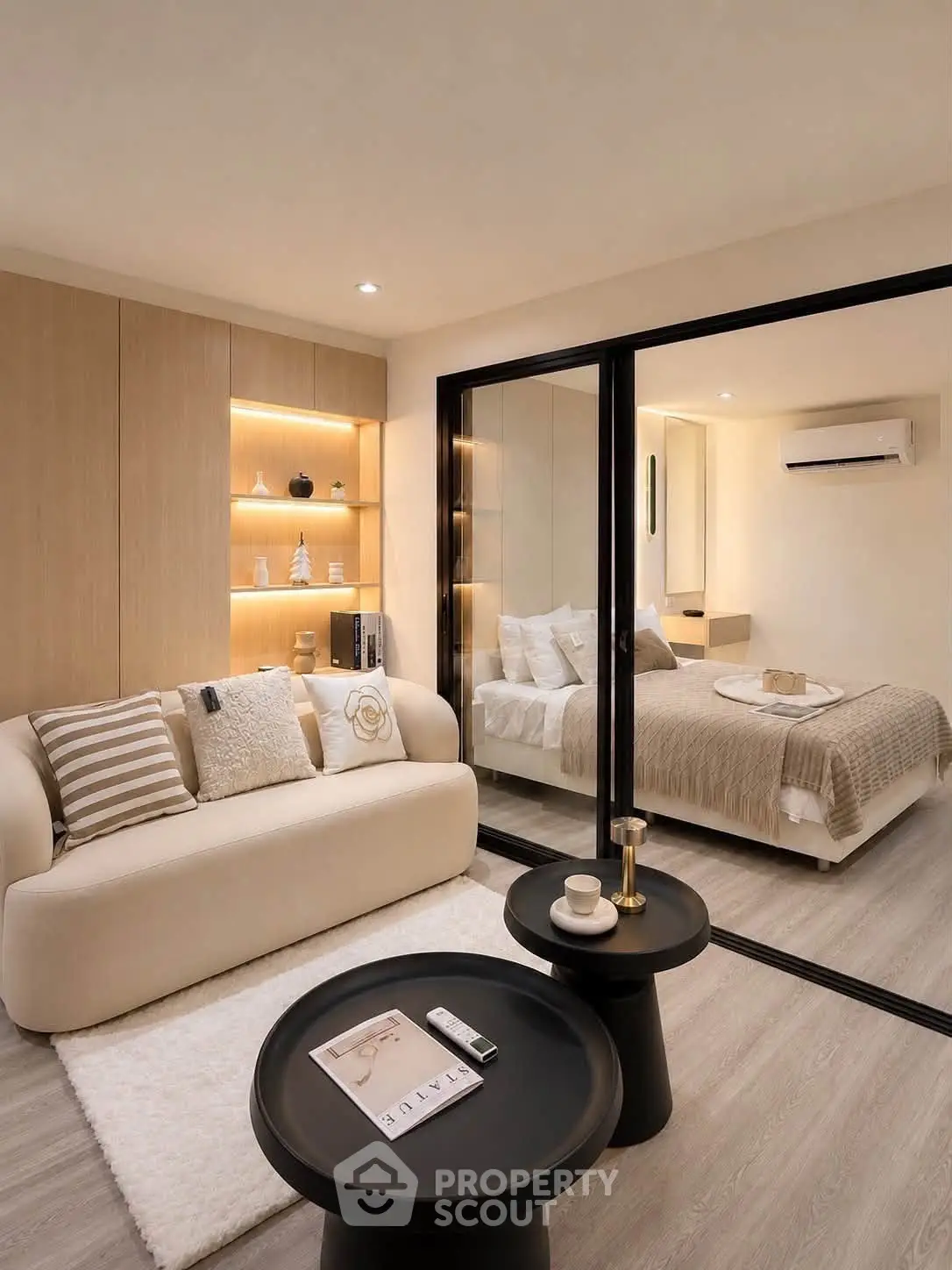 Modern living room with cozy sofa and view into elegant bedroom, featuring stylish decor and warm lighting.