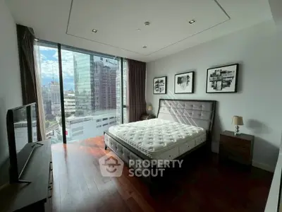 Modern bedroom with city view, featuring sleek furniture and large windows for natural light.