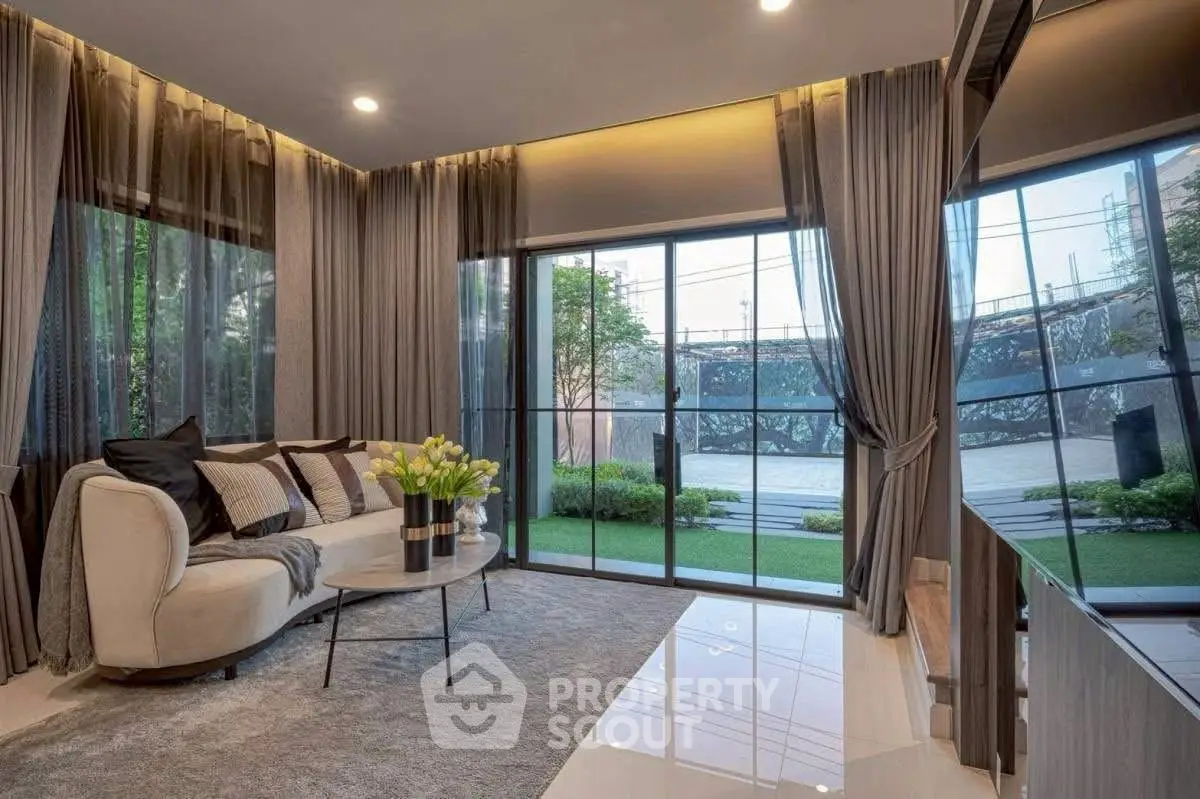Luxurious living room with large windows and elegant decor, offering a serene garden view.