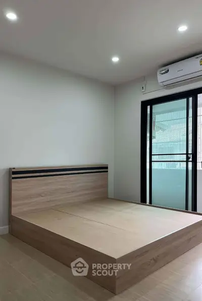 Modern bedroom with minimalist wooden bed and balcony access