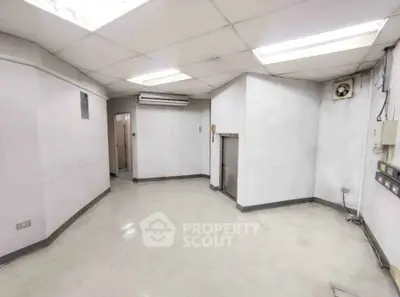 Spacious empty room with white walls and ceiling lights, ideal for customization.