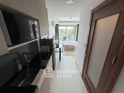 Modern compact kitchen with sleek appliances leading to a bright bedroom with balcony view.