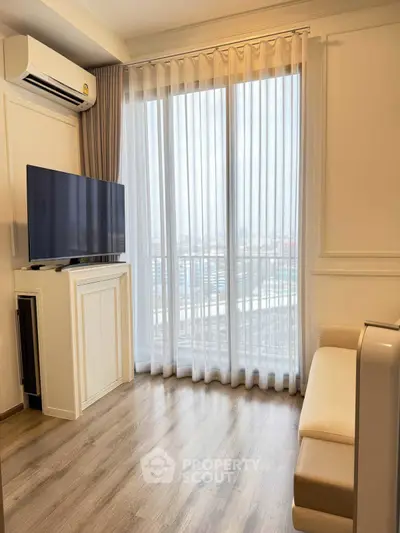 Bright living room with large window, modern TV setup, and elegant flooring.