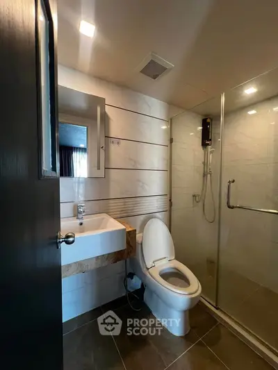 Modern bathroom with glass shower and sleek fixtures in a contemporary apartment.