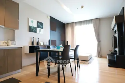Modern open-plan living room with sleek kitchen and stylish dining area, featuring contemporary decor and natural light.
