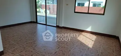 Spacious empty room with tiled flooring and large windows for natural light.