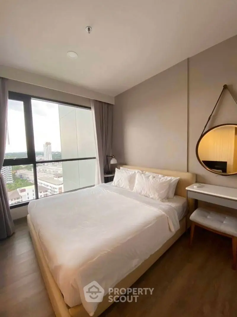 Modern bedroom with large window offering city view, featuring cozy bed and stylish decor.