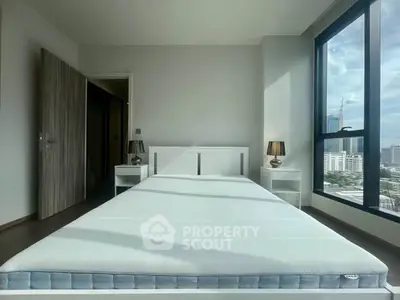 Spacious bedroom with large window offering stunning city views, modern furnishings, and ample natural light.