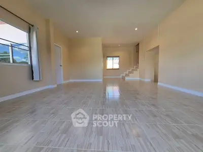 Spacious open-plan living room with tiled flooring and natural light.
