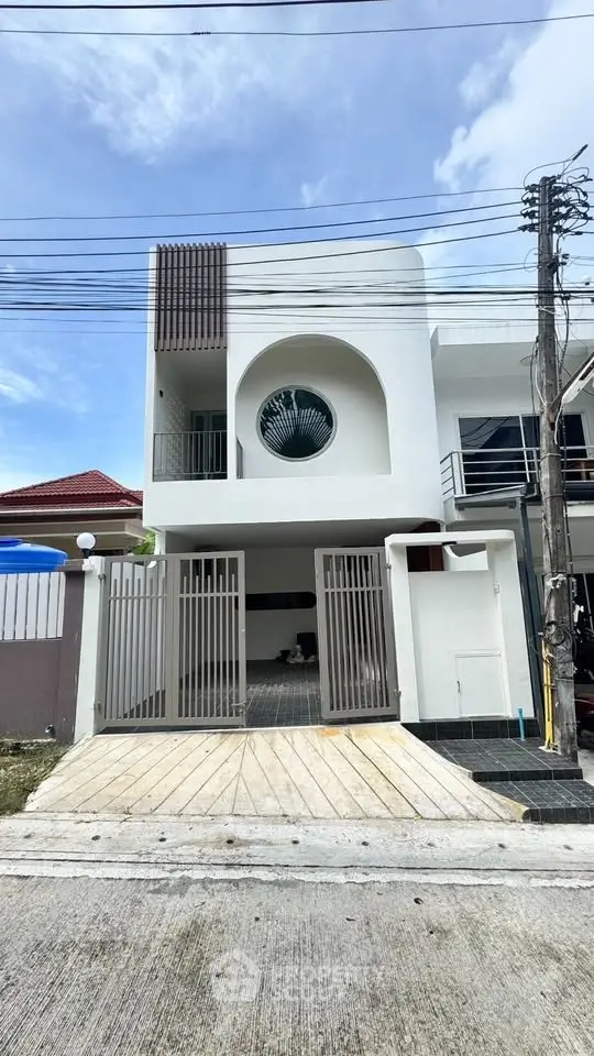Modern two-story house with unique circular window and gated driveway