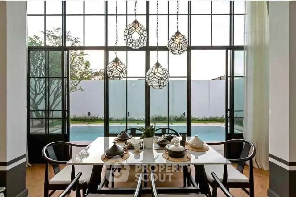 Elegant dining area with modern lighting and pool view, perfect for entertaining.