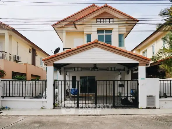 Charming two-story house with gated entrance and tiled roof in a suburban neighborhood.