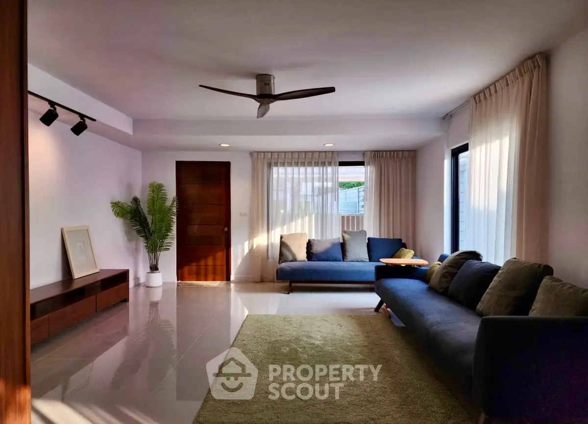Spacious living room with modern decor and natural light, featuring cozy sofas and elegant curtains.
