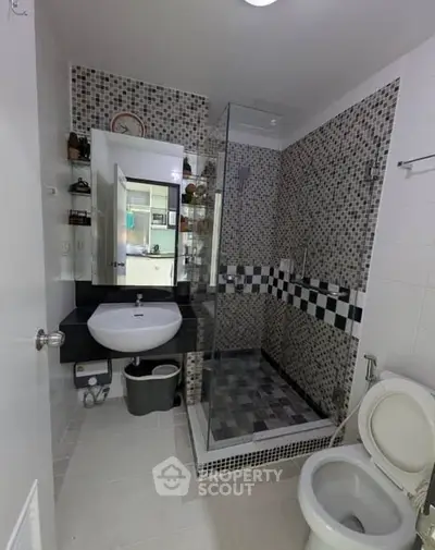 Modern bathroom with stylish mosaic tiles and glass shower enclosure.