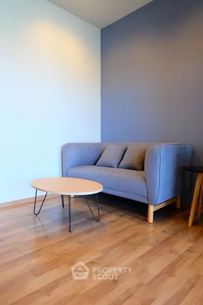 Modern living room with stylish blue sofa and wooden coffee table on sleek hardwood floor.