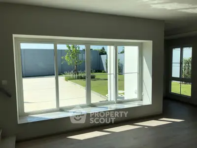 Spacious living room with large window overlooking a modern garden area.