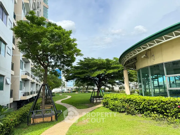 Spacious garden area with lush greenery and modern architecture in a residential complex.