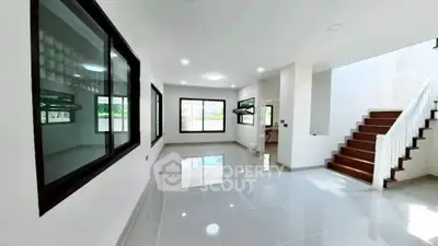 Spacious modern living room with large windows and sleek staircase