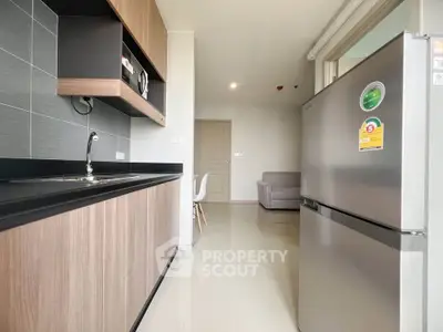 Modern kitchen with sleek cabinets and stainless steel fridge in open layout apartment.