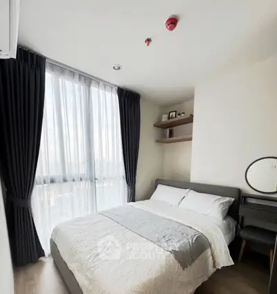 Modern bedroom with large window and elegant decor in a high-rise apartment.