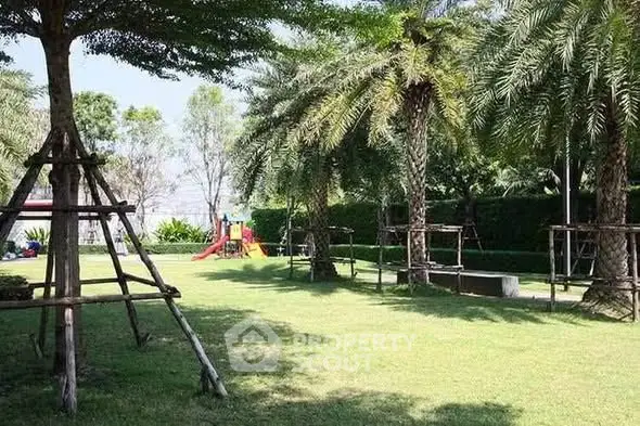Lush green garden with palm trees and a children's play area in a residential complex.