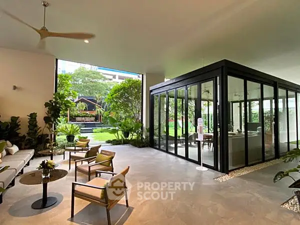 Luxurious open-plan living area with garden view and modern glass enclosure, perfect for relaxation and entertaining.