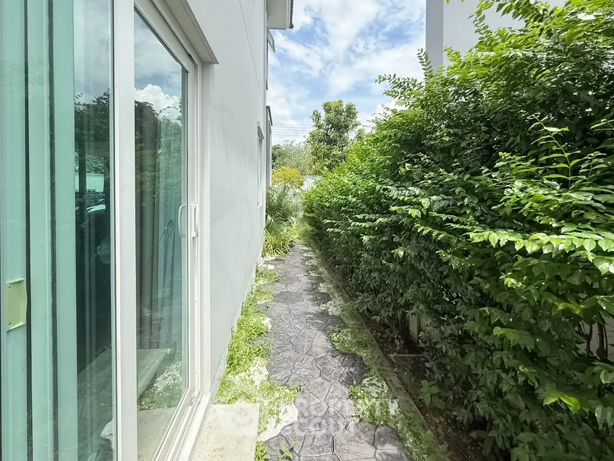 Charming garden pathway beside modern home with lush greenery and sliding glass door
