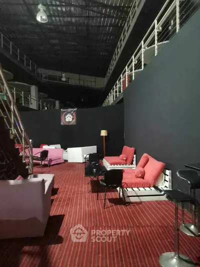 Spacious industrial-style lounge with modern seating and red accents