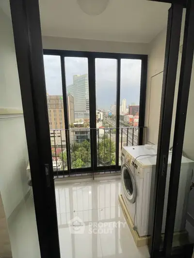 Modern high-rise apartment with city view and washing machine on balcony.