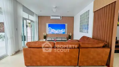 Spacious living room with modern decor and large TV, featuring a cozy brown sofa and elegant design.