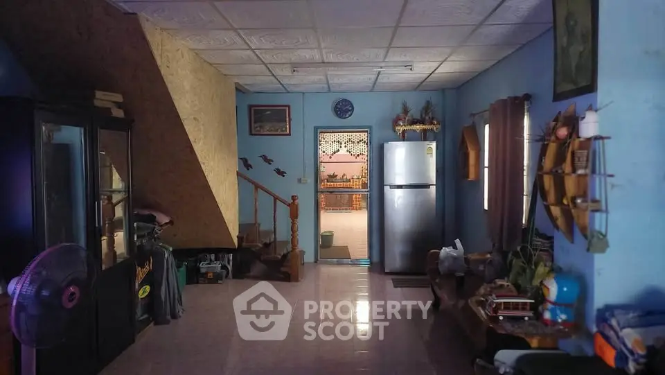 Charming rustic living area with staircase and fridge, perfect for cozy family gatherings.
