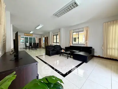 Spacious living room with modern black leather sofas and large windows for natural light.