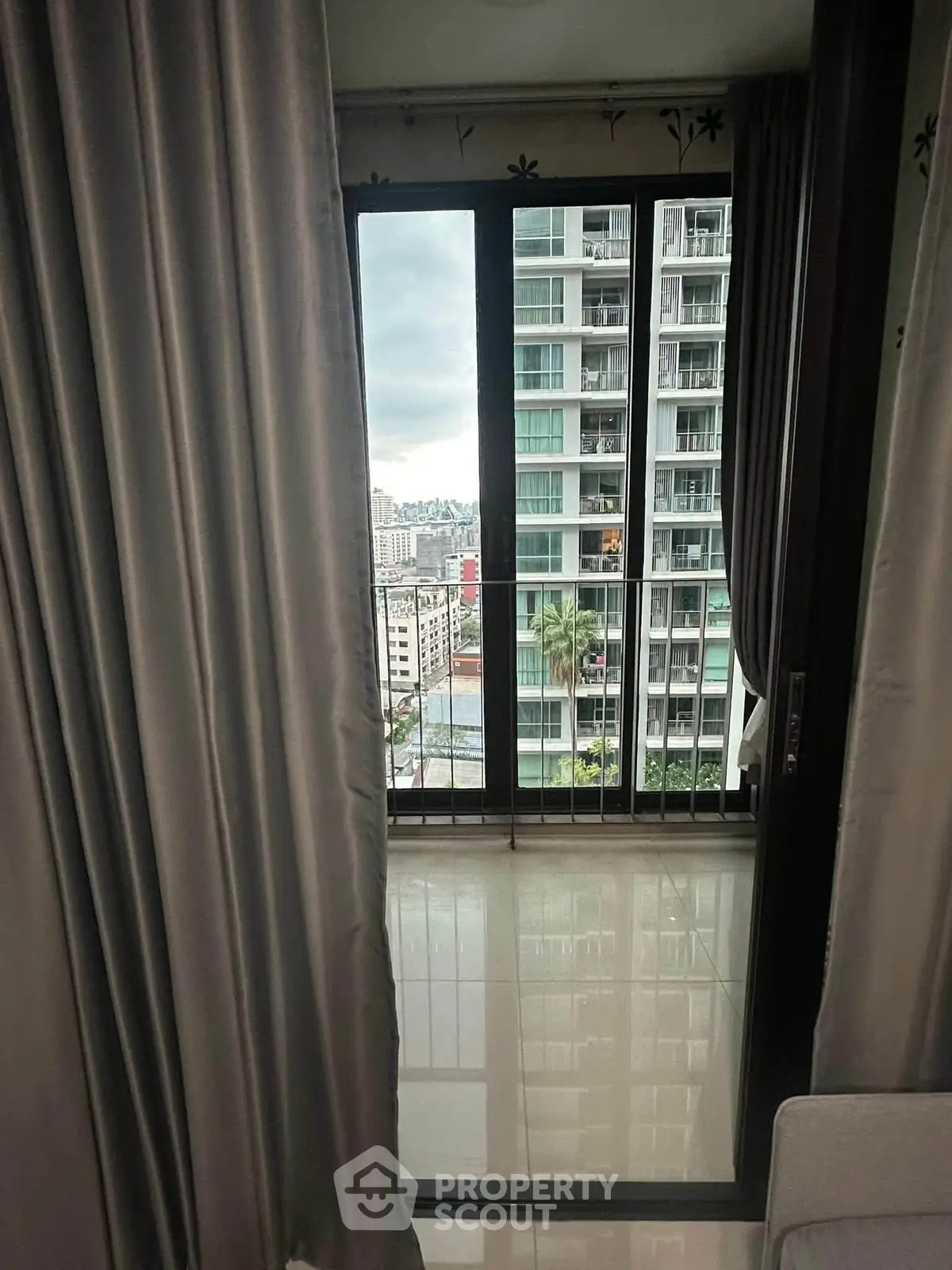 Modern apartment with balcony offering cityscape views, featuring sleek curtains and glossy flooring.