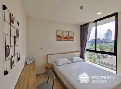 Bright and airy bedroom with a large window offering a city view, modern furnishings, and a cozy ambiance perfect for relaxation.