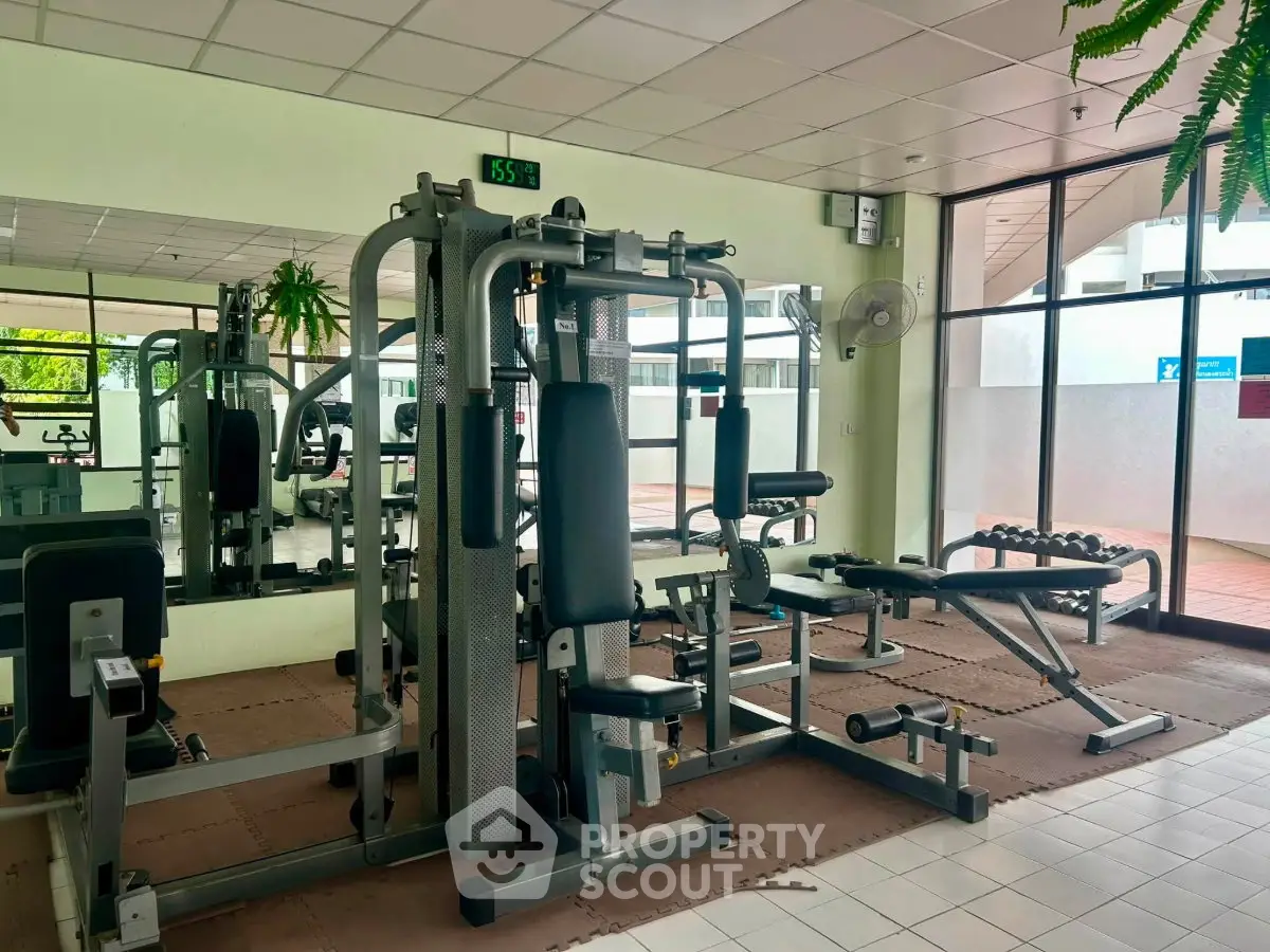 Spacious gym with modern equipment and mirrored walls in a residential building.