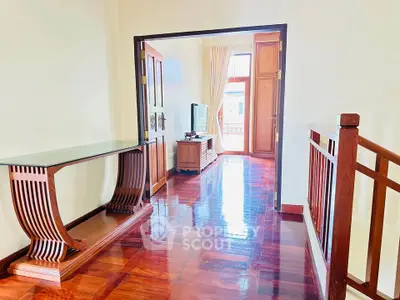 Elegant hallway leading to a bright living room with polished wooden floors and stylish furniture.
