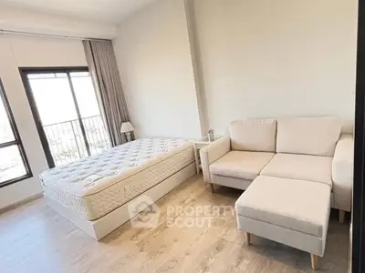 Modern bedroom with cozy sofa and large window offering natural light and city view.