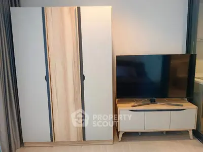 Modern living room with sleek wardrobe and flat-screen TV on stylish stand.