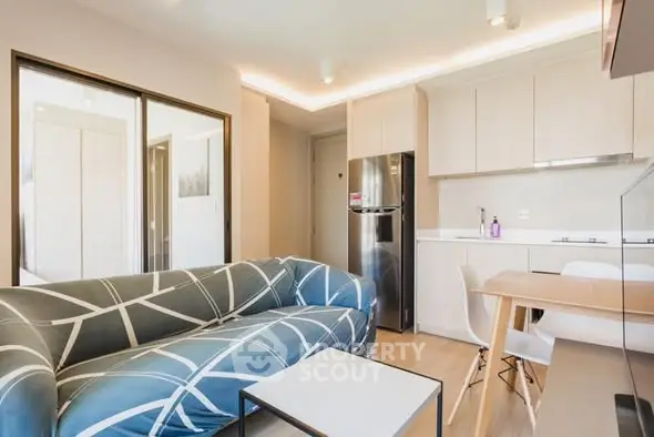 Modern living room with stylish sofa and sleek kitchen in open layout apartment.