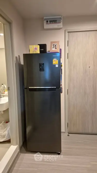 Modern apartment interior with sleek stainless steel refrigerator near entrance.