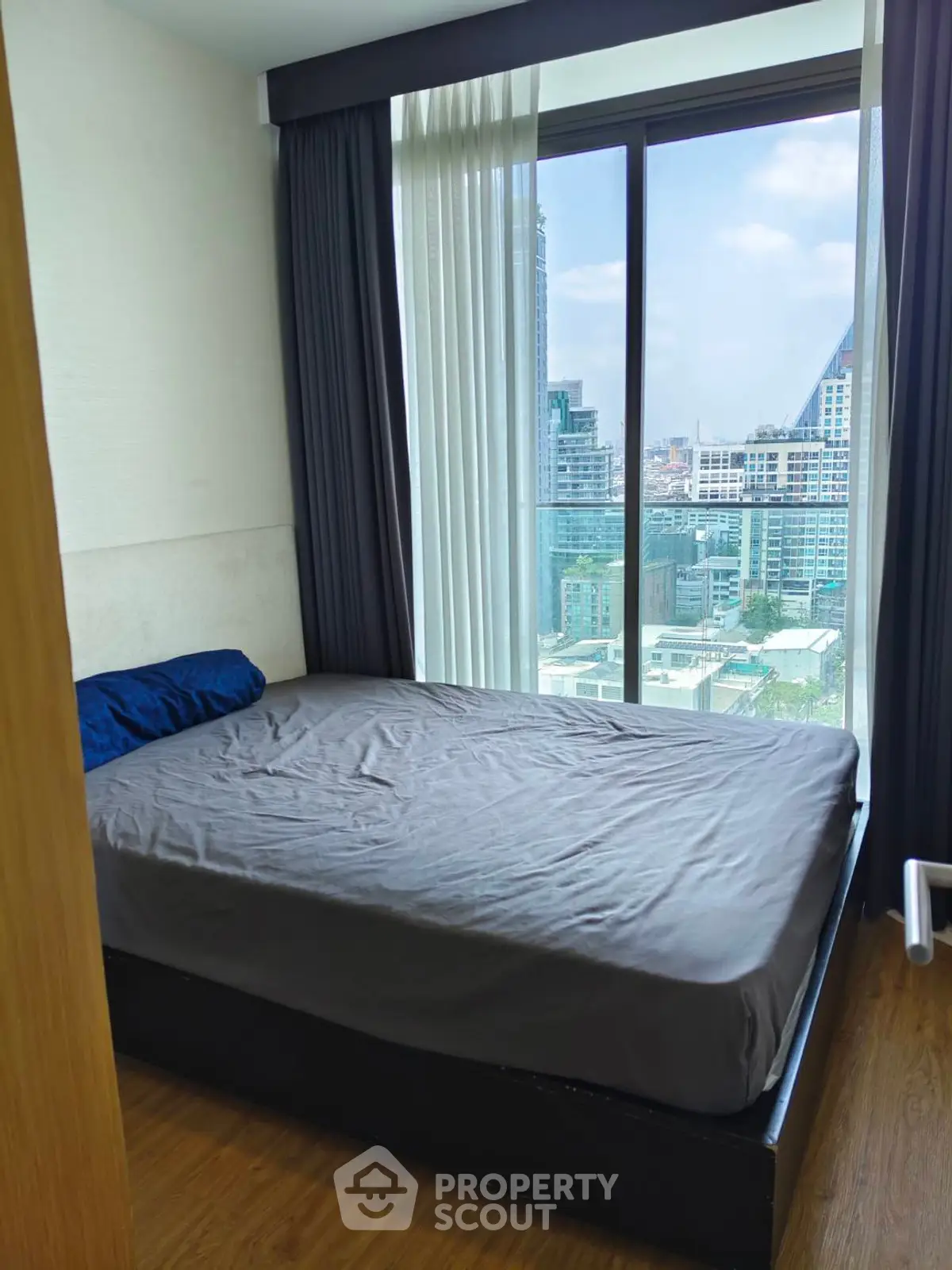 Modern bedroom with large window offering stunning city view in high-rise apartment