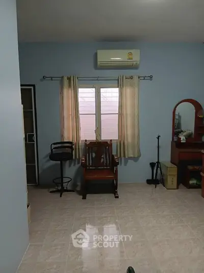 Cozy room with air conditioning and natural light, featuring a wooden chair and vanity desk.
