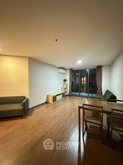 Spacious modern living room with wooden flooring and city view balcony.
