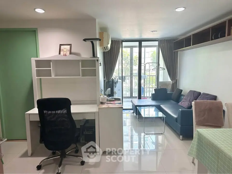 Modern living room with study area and balcony view, featuring sleek furniture and natural light.