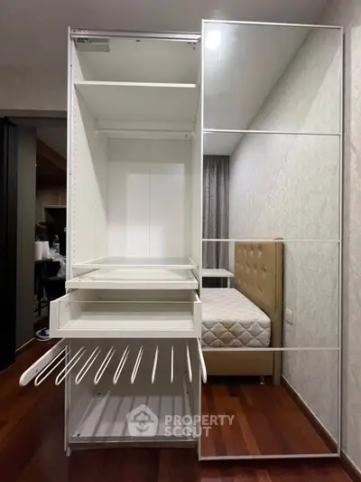Modern bedroom with sleek wardrobe and mirrored sliding doors, showcasing elegant hardwood flooring.