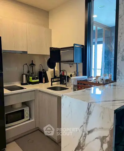 Modern kitchen with sleek appliances and marble countertop in a stylish apartment.