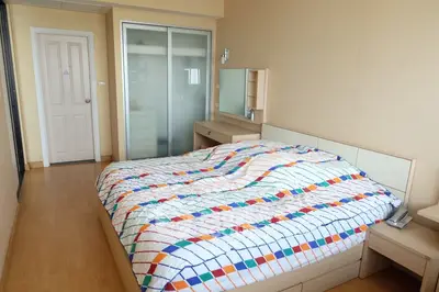 Cozy bedroom with colorful bedding and sliding closet doors in modern apartment.