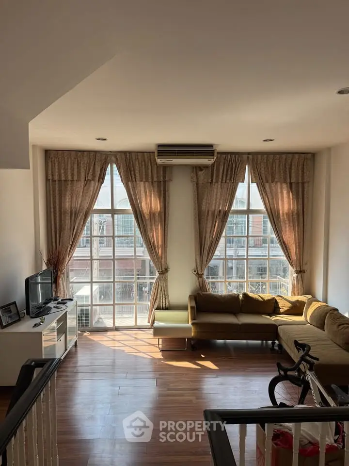 Spacious living room with large windows and modern furnishings in a bright, airy apartment.